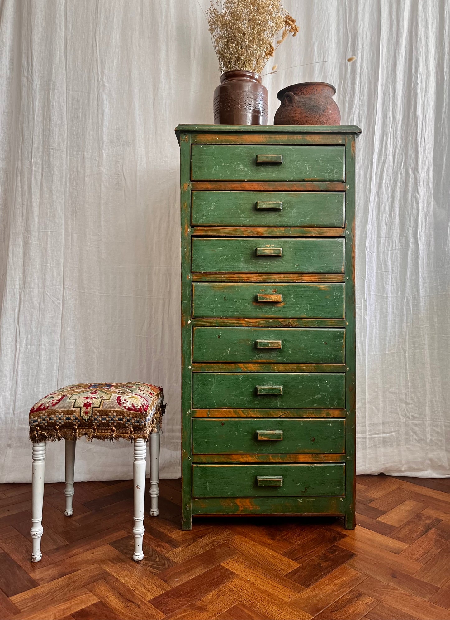 Vintage handmade 1940s green painted wooden tallboy with vintage french utensil pot, antique stone ware cooking pot, and a hand sewn antique folk art tapestry stool