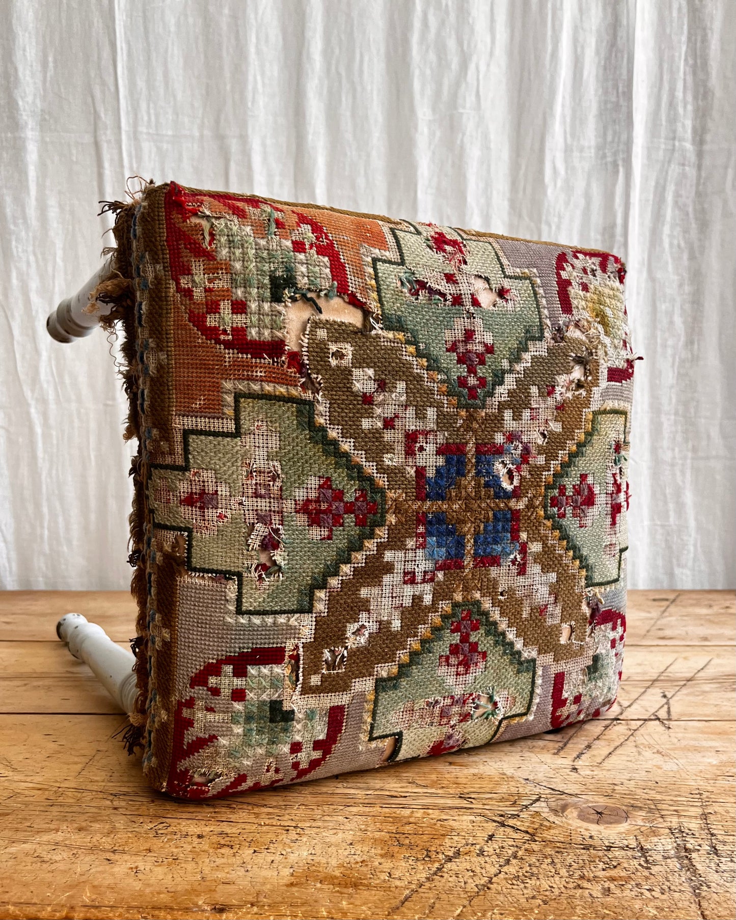 white painted antique folk art stool with a hand sewn striking tapestry seat cover