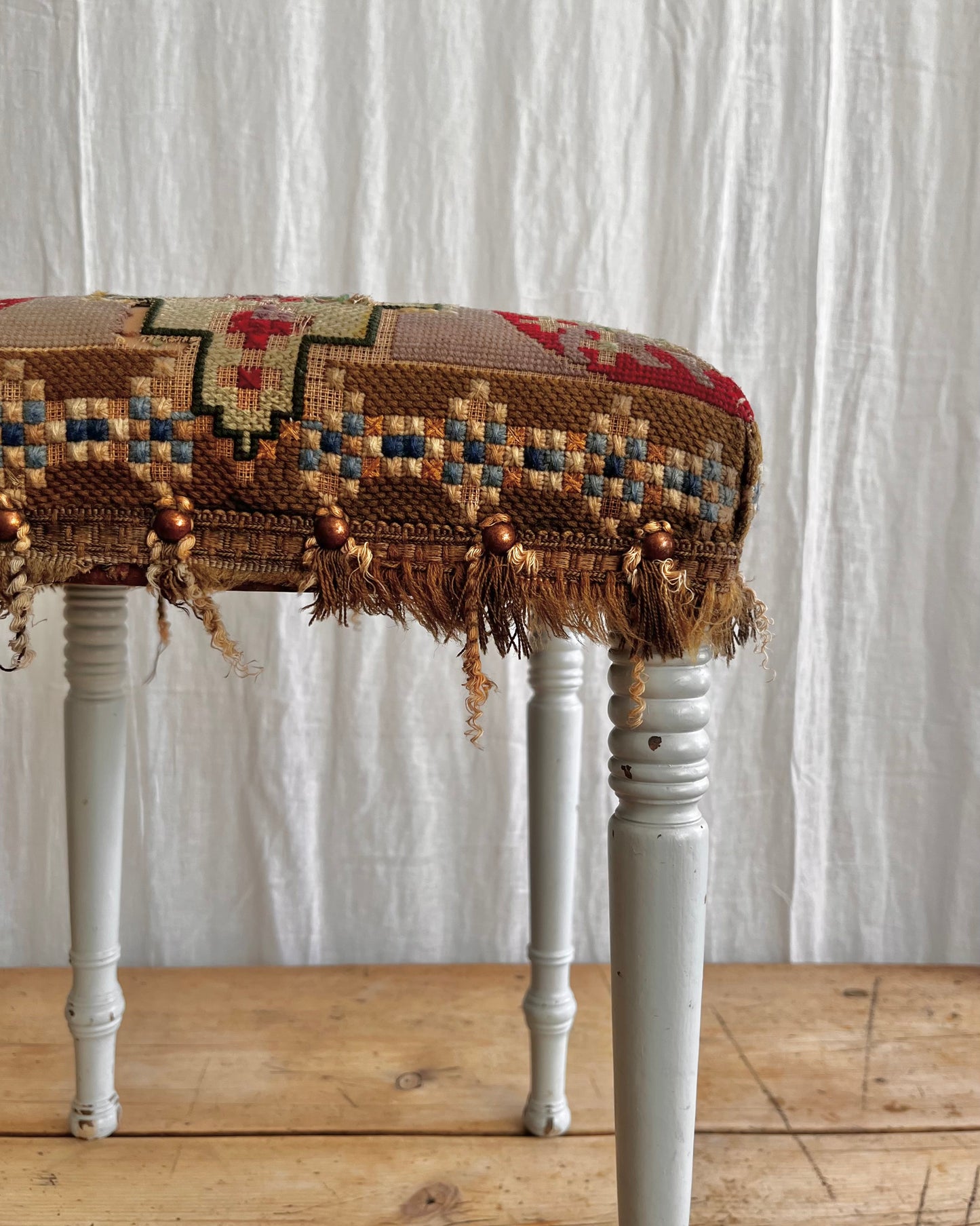 white painted antique folk art stool with a hand sewn striking tapestry seat cover