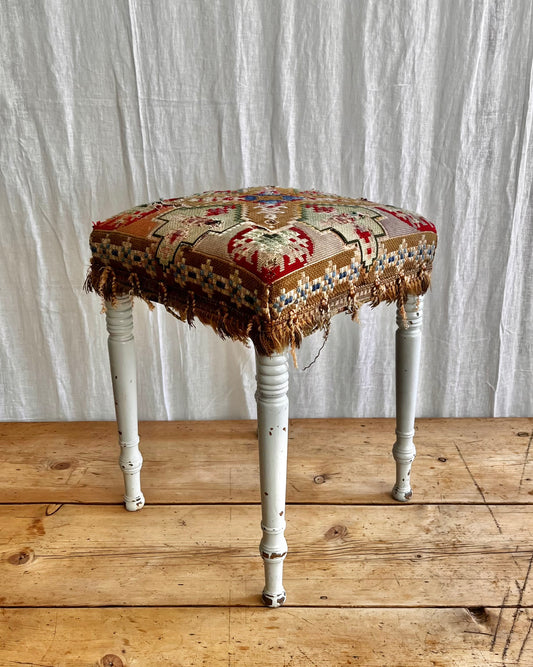 white painted antique folk art stool with a hand sewn striking tapestry seat cover