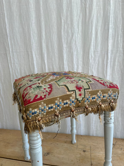 white painted antique folk art stool with a hand sewn striking tapestry seat cover