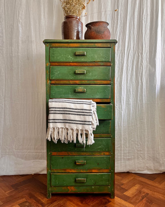 Vintage handmade 1940s green painted wooden tallboy with vintage french utensil pot, antique stone ware cooking pot, and a white and black striped and tasseled blanket